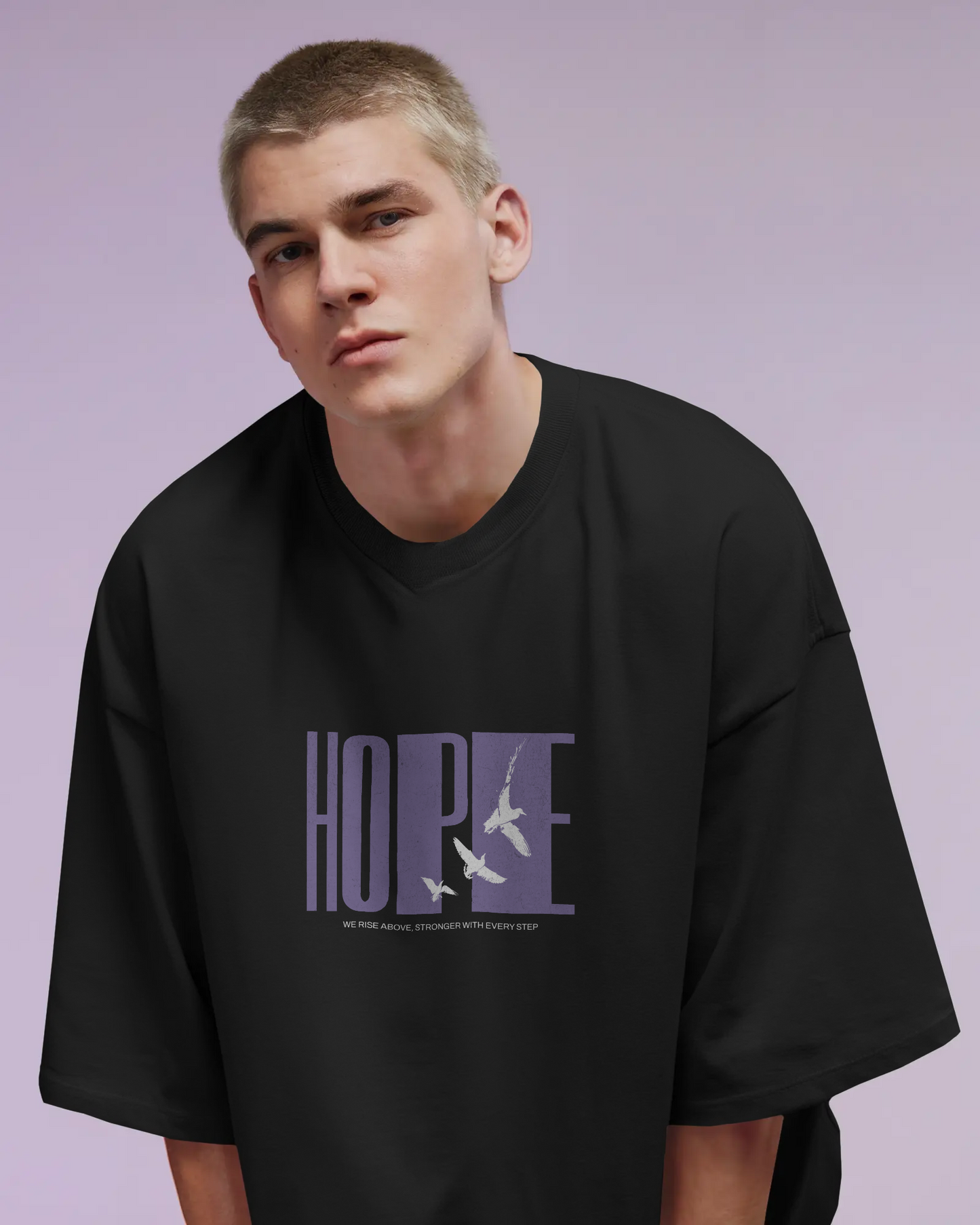 a man wearing Qurrito’s Black Hope Oversized T-Shirt, featuring minimalist bird graphics and lavender typography. The bold yet calm design reflects confidence and focus, ideal for modern men’s oversized streetwear or casual bold looks.