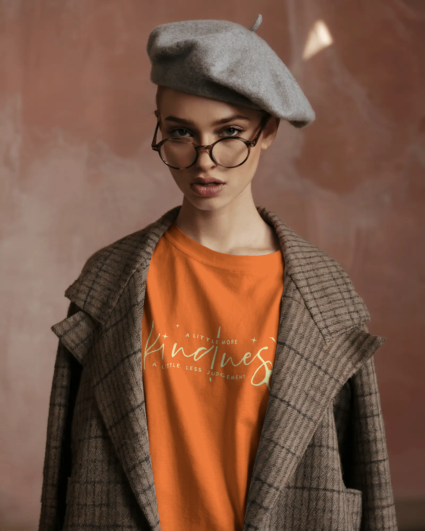 Stylish woman in beret and coat wearing Qurrito’s Kindness Orange T-Shirt, featuring a motivational quote. The regular fit cotton tee expresses romantic, affectionate, happy, and cheerful moods — an effortlessly positive statement piece for women.