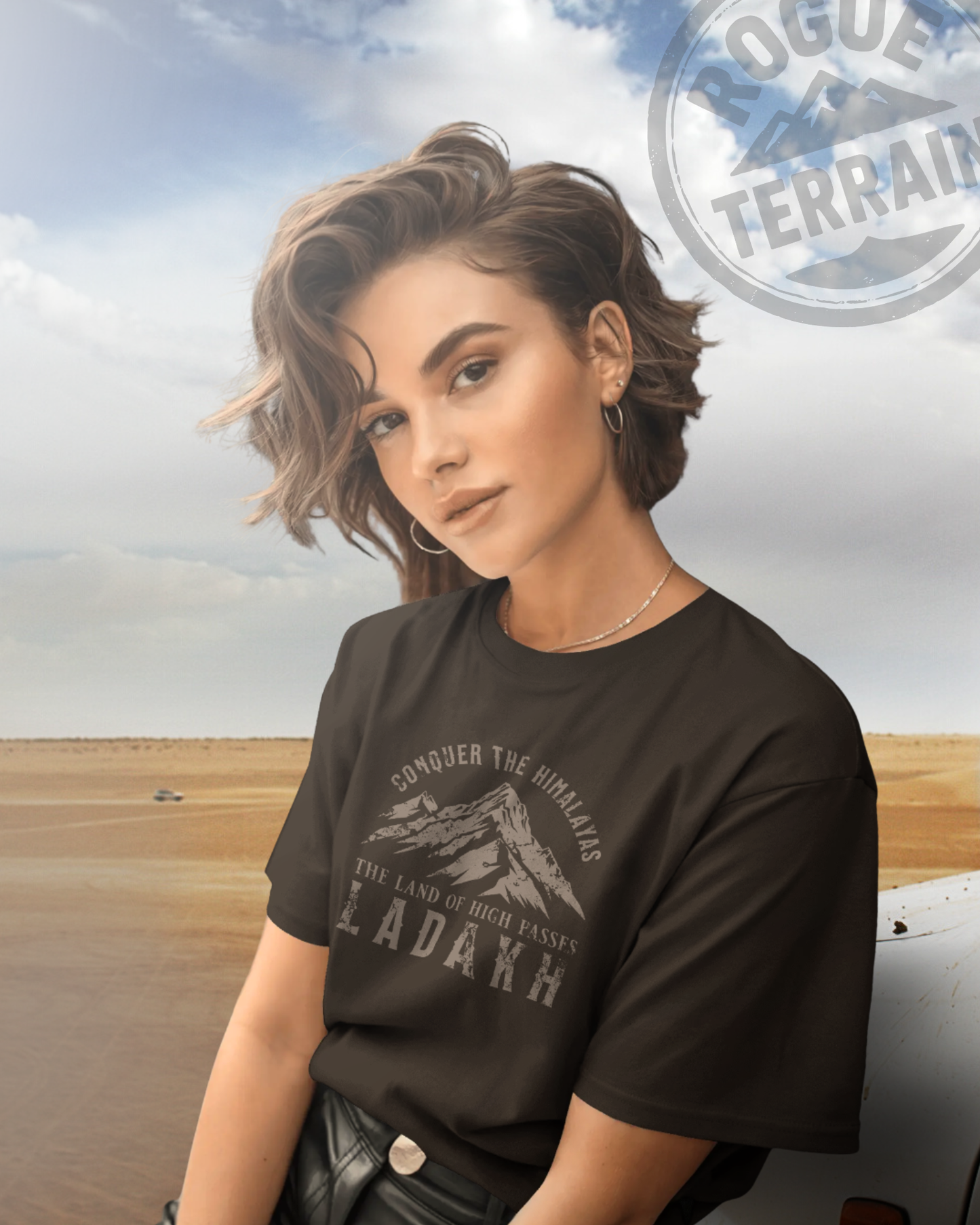 Female model styled in Qurrito’s Mountain Graphic Ladakh Travel T-Shirt in coffee brown. The regular-fit cotton tee blends serious, focused, chill, relaxed, happy, and cheerful moods with bold Himalayan-inspired typography — a perfect fit for explorers and streetwear lovers.