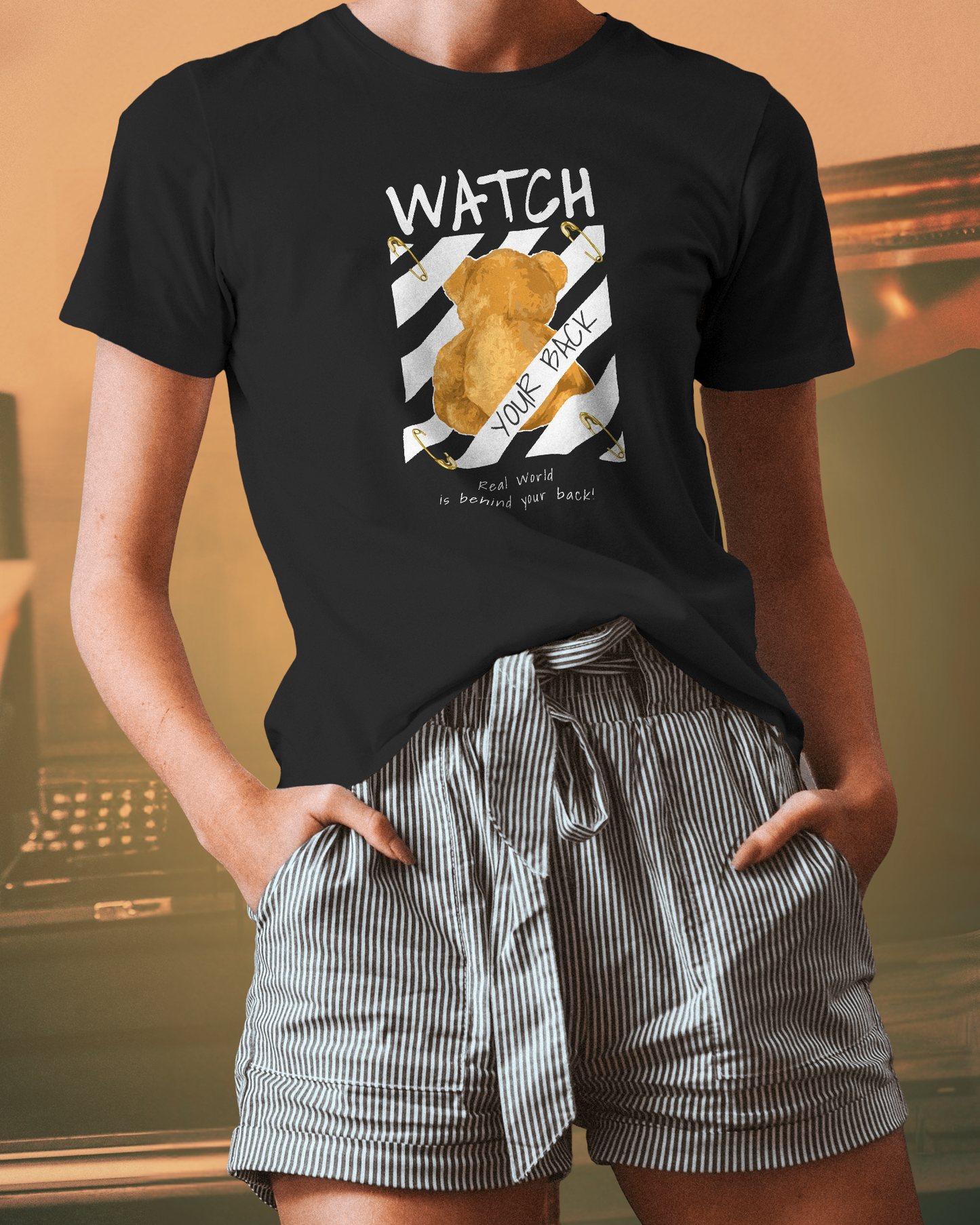 Woman styling Qurrito’s Watch Your Back Black Graphic T-Shirt – Regular Fit with striped paperbag shorts, creating a quirky, confident mood, and casual streetwear outfit for women. Perfect for searches like “women’s graphic tee with shorts” or “summer streetwear look for women.”