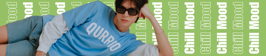 Gen-Z model in a blue oversized Qurrito mood-based t-shirt lounging in a relaxed pose against a green background with ‘Chill Mood’ text — showcasing Qurrito’s mood-driven streetwear style.