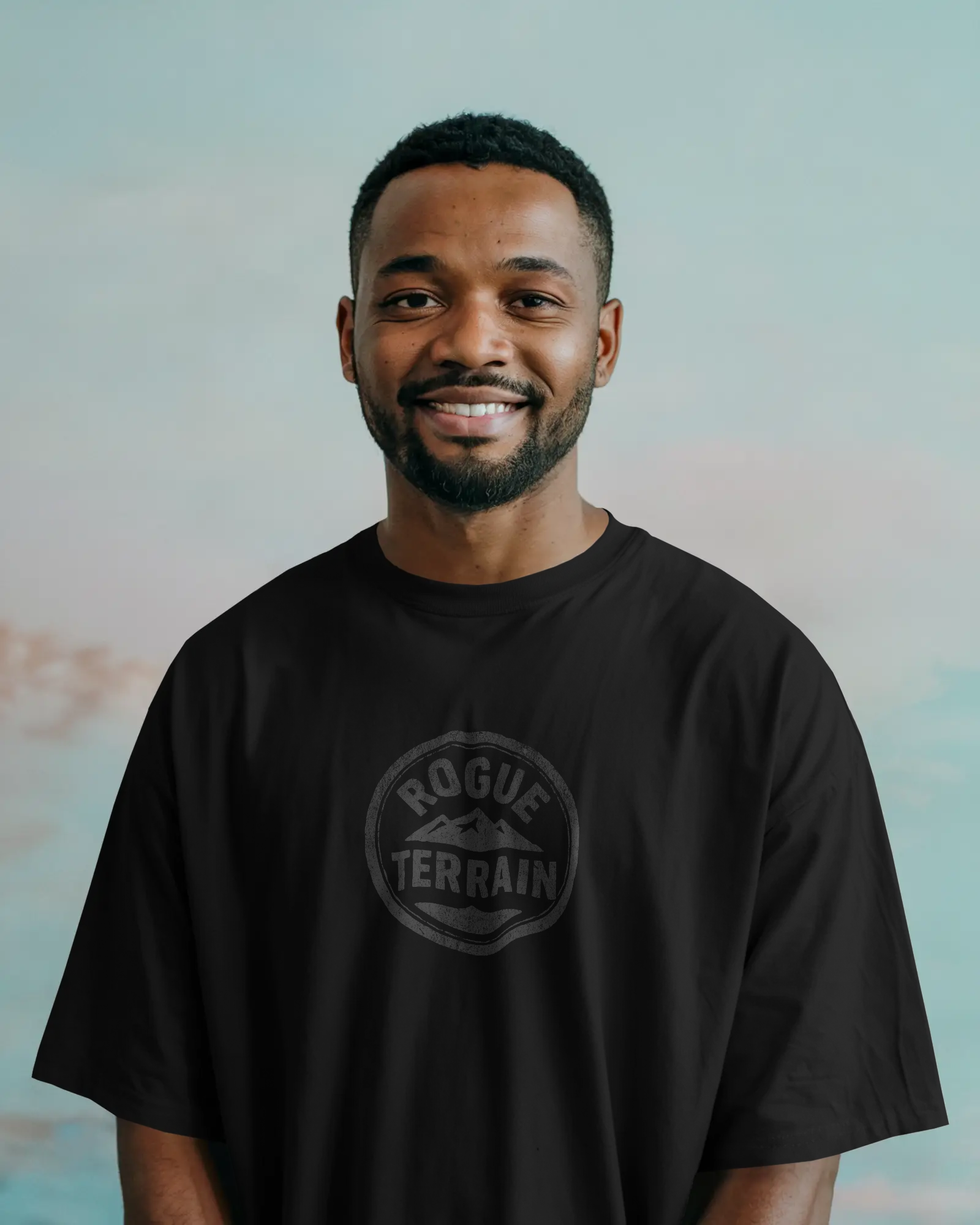 A man wearing Urban Outdoor T-Shirt – Black Rogue Terrain Oversized Tee by Qurrito