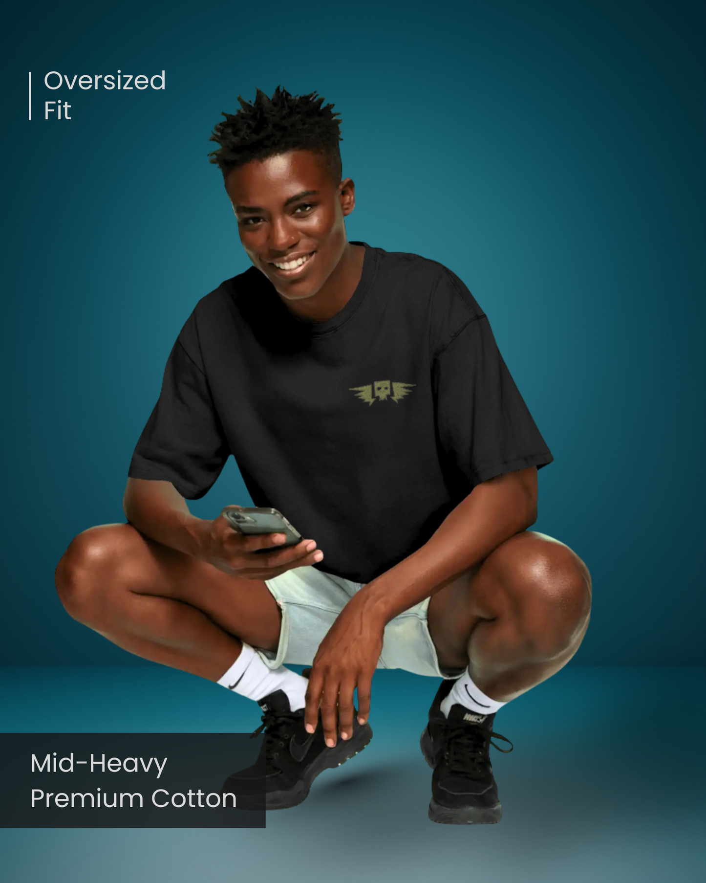 Man wearing Qurrito’s Embroidered Winged Skull Oversized T-Shirt made from mid-heavy premium cotton. Styled casually with white shorts and sneakers, this dark streetwear tee reflects confidence and a mysterious bold mood vibe.