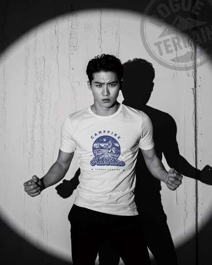 Male model wearing Qurrito’s Campfire Adventure Regular Fit T-Shirt in white, printed with a blue mountain and camping graphic. This summer cotton tee captures romantic, affectionate, chill, relaxed, happy, and cheerful moods — a perfect choice for outdoor adventure enthusiasts.