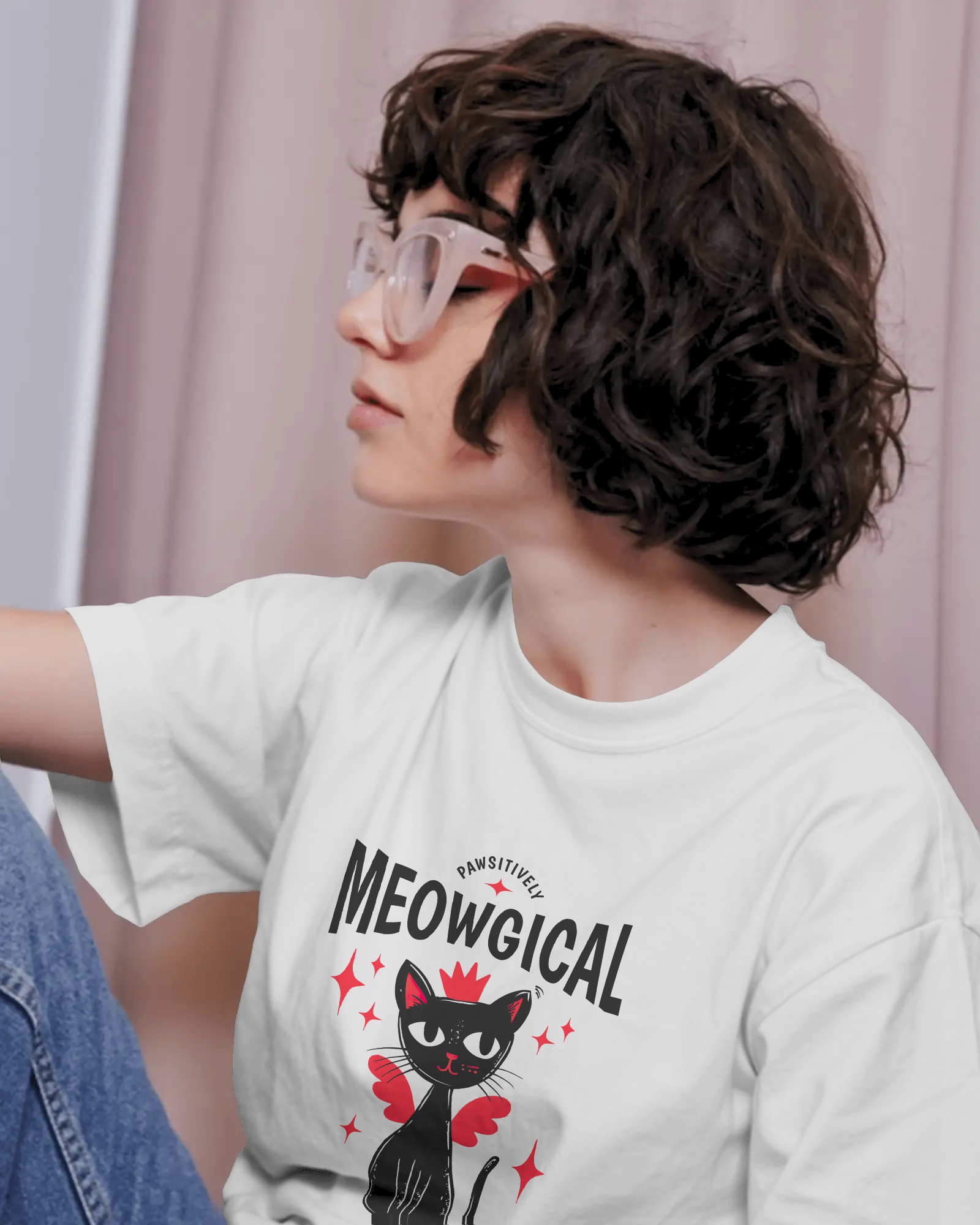 Female model wearing Qurrito’s Meowgical Magic Cat Wings Oversized T-Shirt in white, featuring a cute black cat with red wings and stars graphic, made from extra-heavy luxe cotton in an ultra-oversized fit.