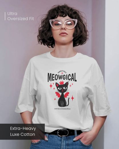 Female model wearing Qurrito’s Meowgical Magic Cat Wings Oversized T-Shirt in white, featuring a cute black cat with red wings and stars graphic, made from extra-heavy luxe cotton in an ultra-oversized fit.