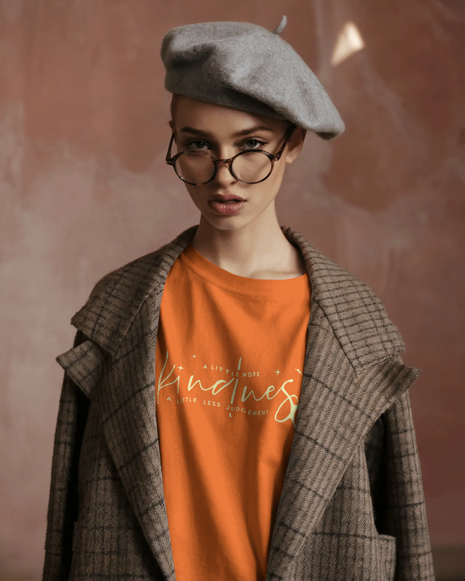 Stylish woman in beret and coat wearing Qurrito’s Kindness Orange T-Shirt, featuring a motivational quote. The regular fit cotton tee expresses romantic, affectionate, happy, and cheerful moods — an effortlessly positive statement piece for women.