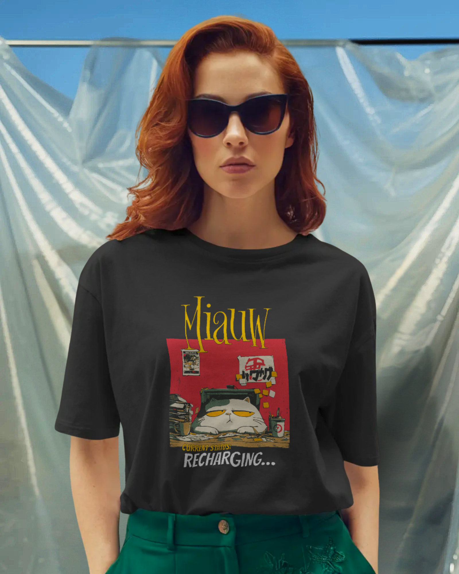 Qurrito Low Battery Mode graphic t-shirt in Regular Fit worn by a woman with sunglasses and red hair. The black tee features a Grumpy Cat Graphic print with a cat sitting on a desk with the text "CURRENT STATUS: RECHARGING..." and "Miauw." Grumpy mood.