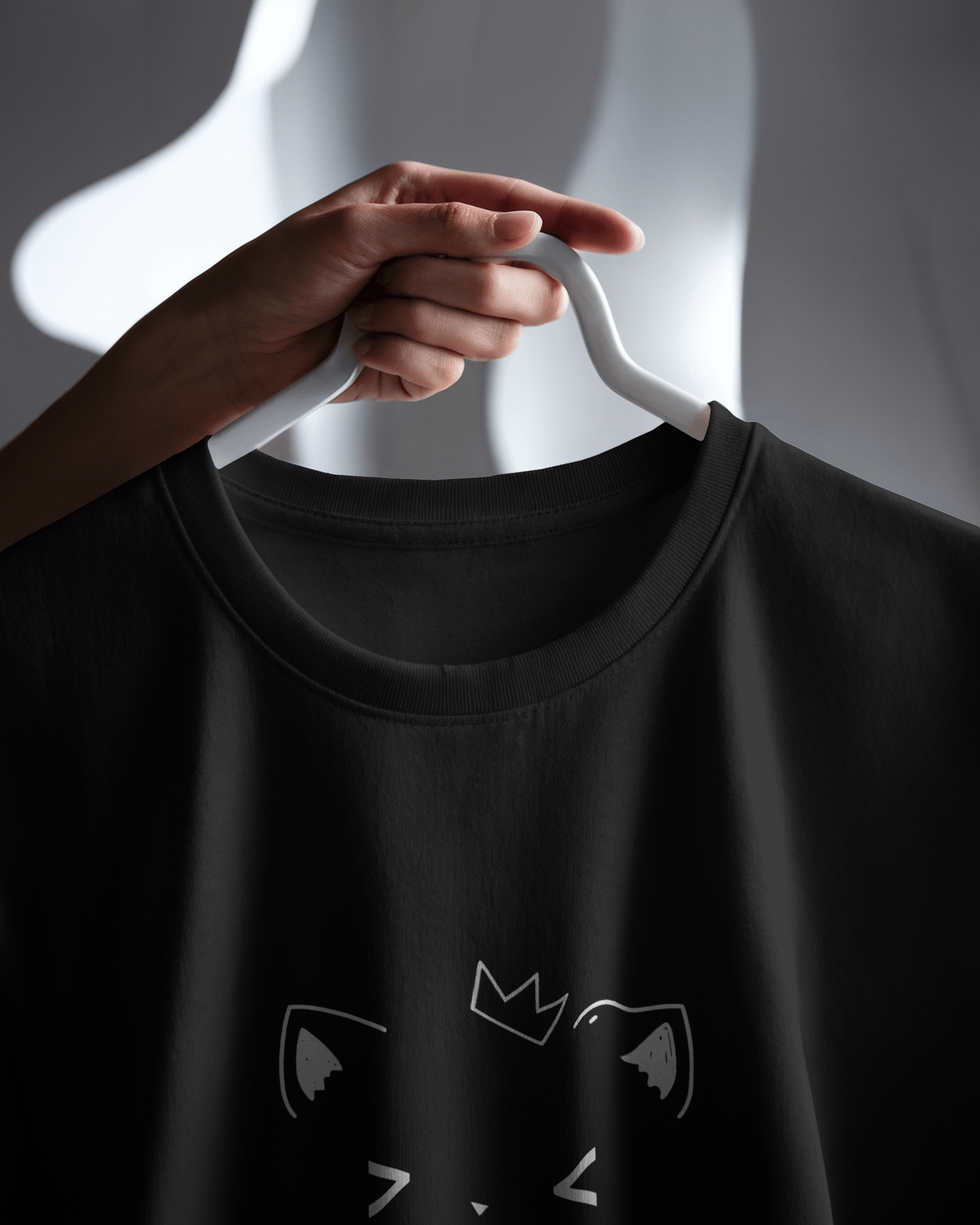Close-up of Qurrito’s Minimal Cat Face T-Shirt in subtle black cotton. The clean graphic and soft texture reflect a chill, relaxed mood — perfect for everyday minimalist streetwear vibes.