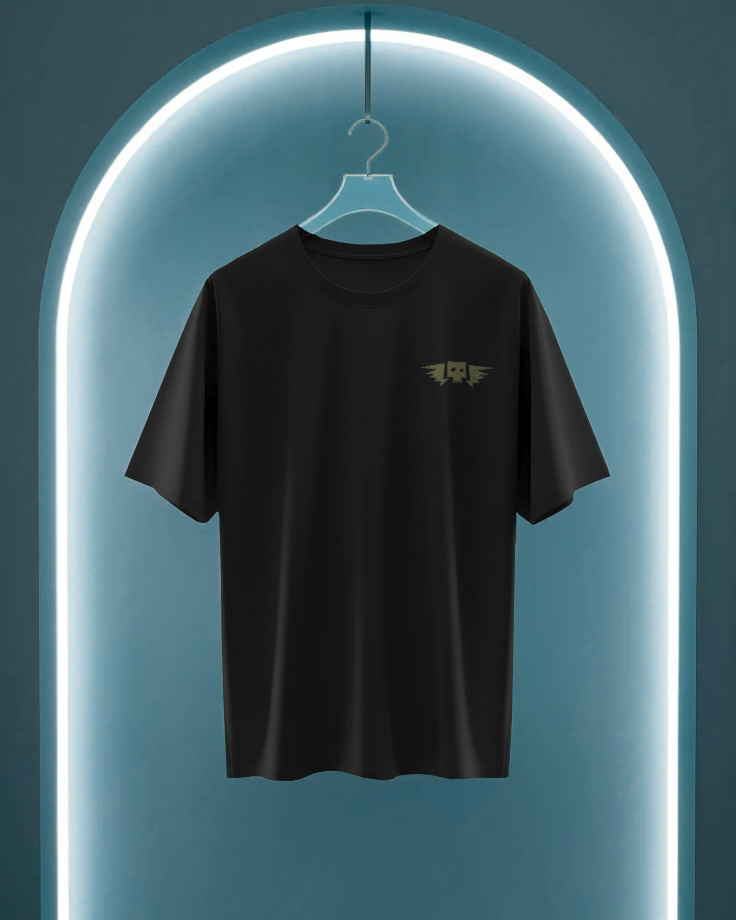 Qurrito’s Black Oversized T-Shirt featuring a minimal embroidered winged skull design hanging under neon lighting. The clean, dark aesthetic embodies mystery and bold streetwear appeal, perfect for unisex oversized fashion.