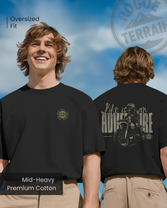 Male model wearing Qurrito’s Motorbike Graphic Oversized T-Shirt in black, featuring “Life is an Adventure” rider artwork on the back. This mid-heavy premium cotton tee radiates energetic, pumped, confident, and bold vibes — perfect for thrill-seekers and travel lovers who embrace freedom on the road.