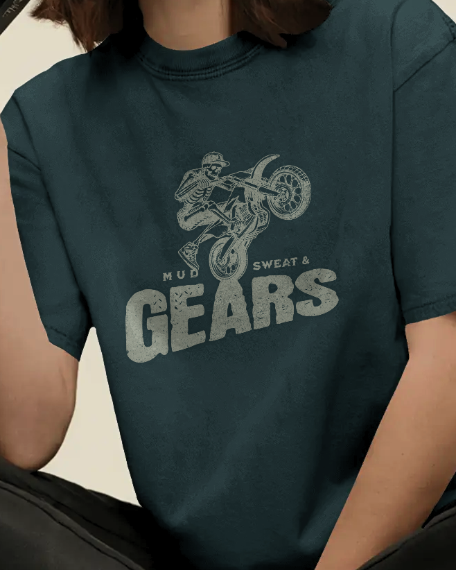 Female model styled in Qurrito’s Mud Biker Skeleton Graphic T-Shirt, showcasing the “Mud Sweat & Gears” motorbike print. The regular-fit tee radiates energetic, pumped, mysterious, and dark moods, blending bold biker aesthetics with casual streetwear fashion.