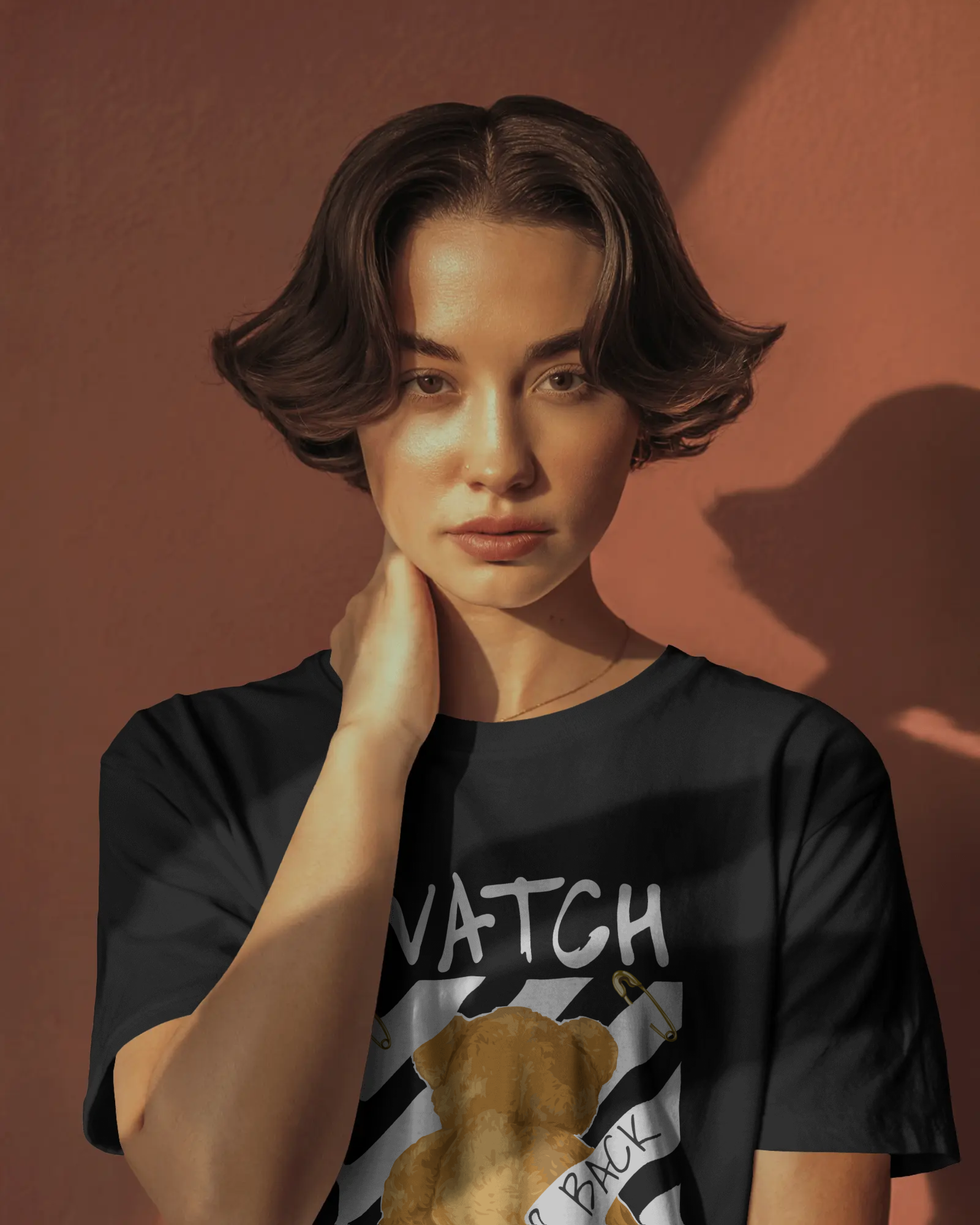 lack regular fit t-shirt featuring a back-facing teddy bear graphic with warning stripes, bold text “Watch Your Back,” and the phrase “Real world is behind your back.” Urban Graphic Wear by Qurrito.