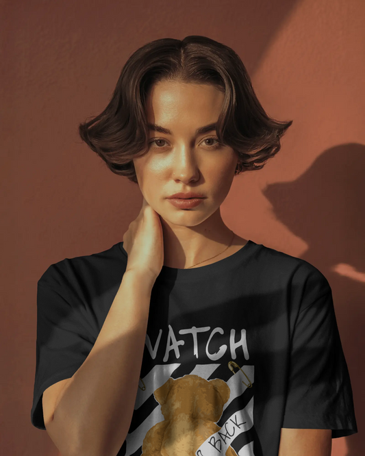 lack regular fit t-shirt featuring a back-facing teddy bear graphic with warning stripes, bold text “Watch Your Back,” and the phrase “Real world is behind your back.” Urban Graphic Wear by Qurrito.