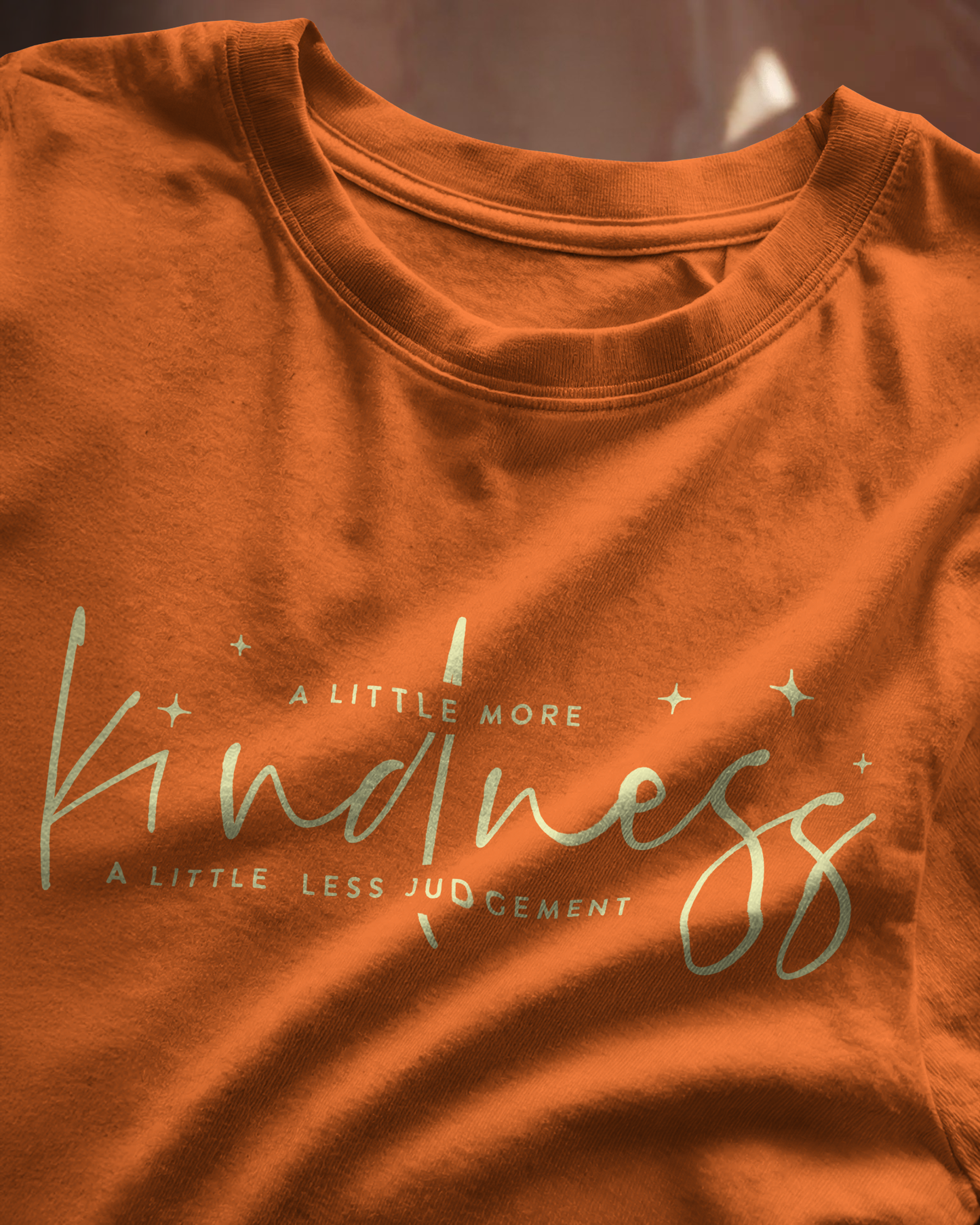 Close-up of Qurrito’s Kindness Orange T-Shirt showcasing soft cotton texture and minimal typography. The design blends cheerful, affectionate, romantic, and happy moods — a feel-good fashion essential for modern women who believe in kindness.