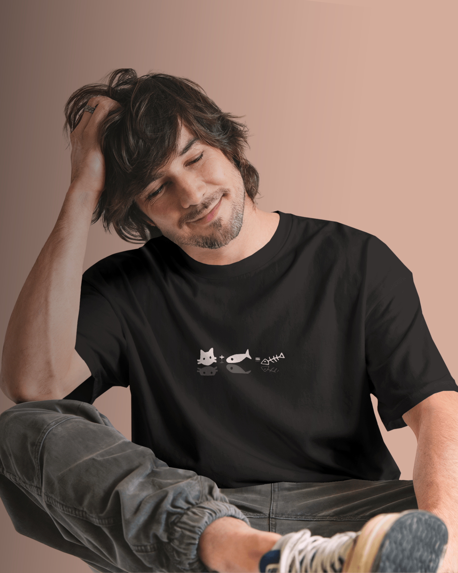 Man wearing Qurrito’s Cat & Fish Equation Regular Fit T-Shirt in black cotton. The minimalist graphic tee expresses a playful, quirky mood with its witty cat and fish equation design — perfect for casual streetwear lovers.
