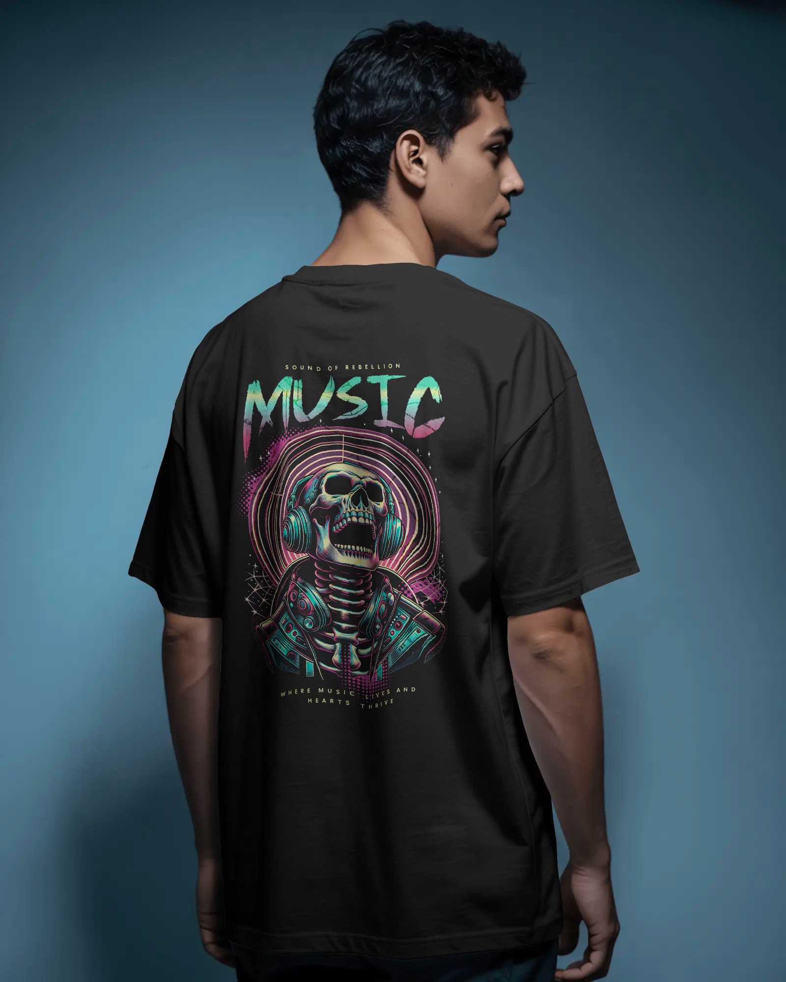 Man styling Qurrito’s Oversized Punk Rock Music T-Shirt – Sound of Rebellion Edition with dark jeans for a bold, mysterious, and confident streetwear look. The neon skull-headphones back print captures punk and grunge energy, trending among music lovers and urban fashion enthusiasts.
