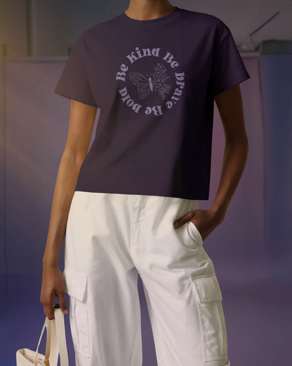 Model posing in Qurrito’s Be Kind Be Brave Be Bold Floral Empowerment T-Shirt paired with a white loose fit cargos and a white tote bag. The minimalist purple tee channels romantic, happy, and cheerful moods — ideal for confident, affectionate personalities who love uplifting fashion.