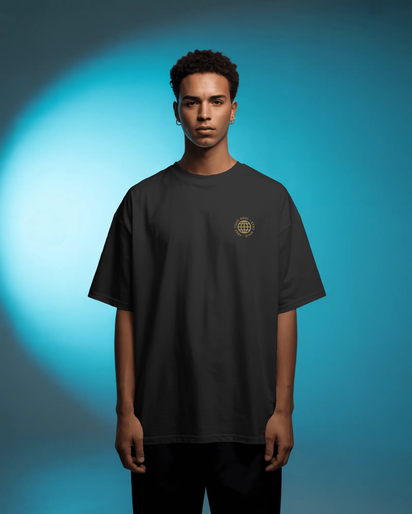 A male model wearing Qurrito’s Black Oversized Streetwear T-Shirt featuring the “Free Your Soul” embroidered golden logo, posed against a blue spotlight background.