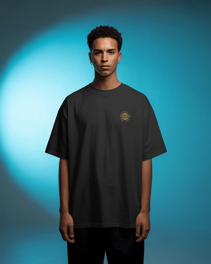 A male model wearing Qurrito’s Black Oversized Streetwear T-Shirt featuring the “Free Your Soul” embroidered golden logo, posed against a blue spotlight background.