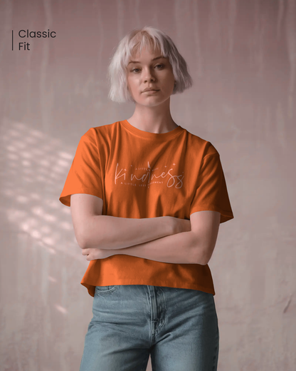 Female model wearing Qurrito’s Regular Fit Cotton T-Shirt in vibrant orange with “A Little More Kindness” text print. This tee radiates happy, cheerful, romantic, and affectionate energy — perfect for everyday wear that uplifts your mood and style.