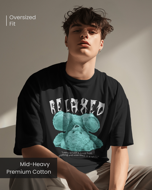 Male model wearing Qurrito’s Relaxed Teddy Graphic Tee in black with teal teddy bear design and gothic “RELAXED” typography, made from mid-heavy premium cotton for a relaxed oversized streetwear vibe.