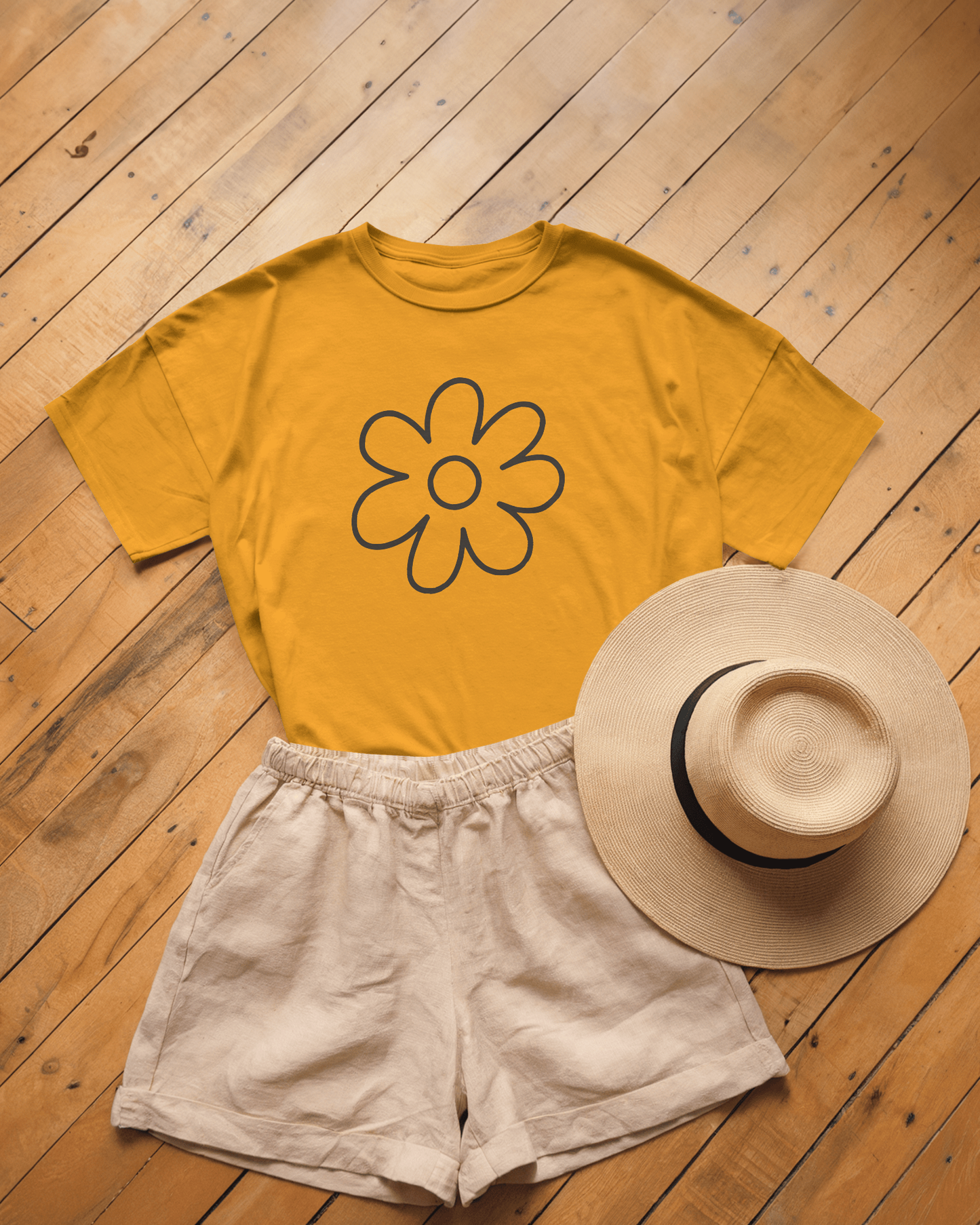 Romantic and chill flat lay of the Yellow Floral Graphic T-Shirt paired with linen shorts and a wide-brimmed straw hat. This cheerful regular-fit unisex tee is the perfect summer outfit drop for an affectionate vibe.