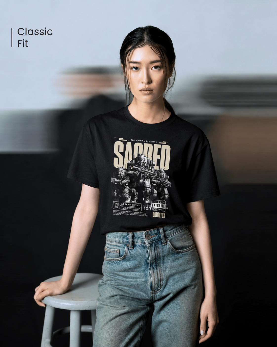 Woman standing with hands in pockets wearing QURRiTO Sacred Mecha Divinity black cyberpunk t-shirt featuring bold SACRED mecha graphic, paired with oversized light wash jeans.