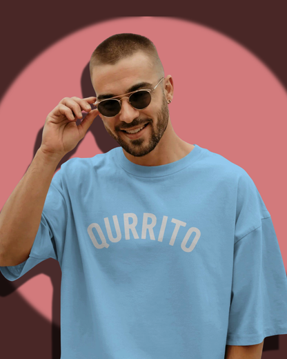 Smiling man wearing Qurrito’s Sky Blue Branded Oversized T-Shirt styled with sunglasses and casual streetwear vibes. The happy, chill mood of this outfit makes it ideal for relaxed summer fashion or everyday casual wear.