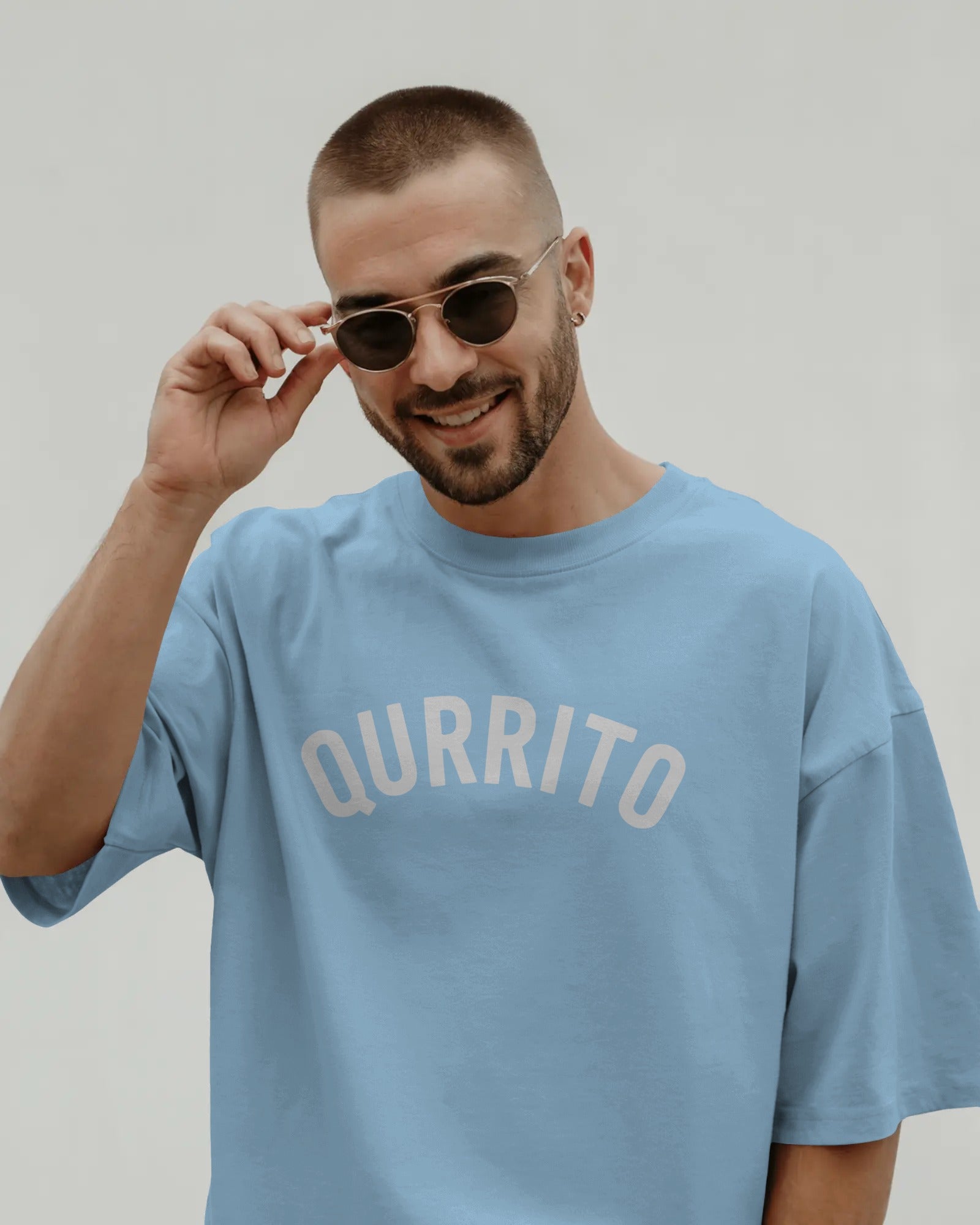 Branded oversized t-shirt for men and women in sky blue with Qurrito arch logo, styled for casual streetwear vibes.