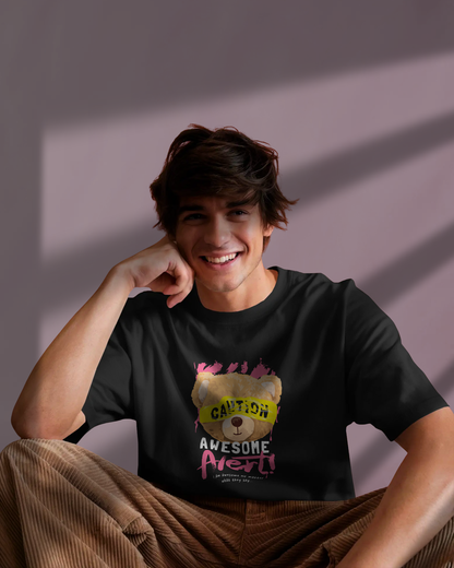 Man smiling in Qurrito’s Caution Teddy Graphic T-Shirt – Regular Fit Casual Wear. The playful teddy bear design with vibrant pink and yellow accents exudes a fun, quirky street vibe.