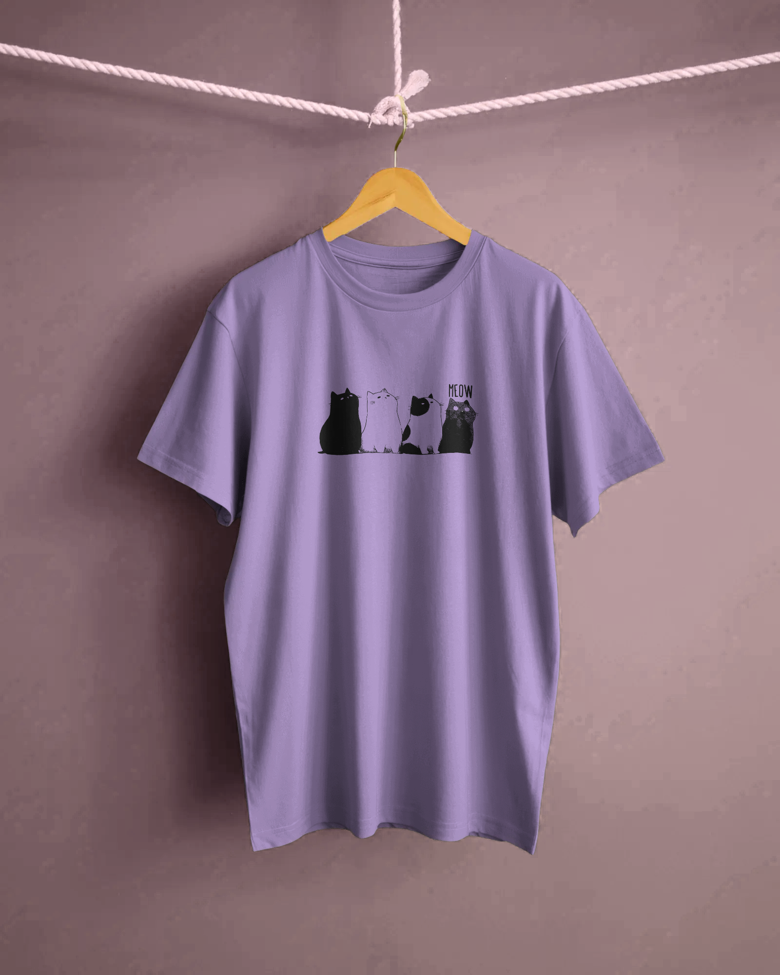 Qurrito The Purr-ple Squad graphic t-shirt in Regular Fit on a hanger. The Lilac tee displays a Chill Cat Graphic print of three black and white cats sitting side-by-side with "MEOW."