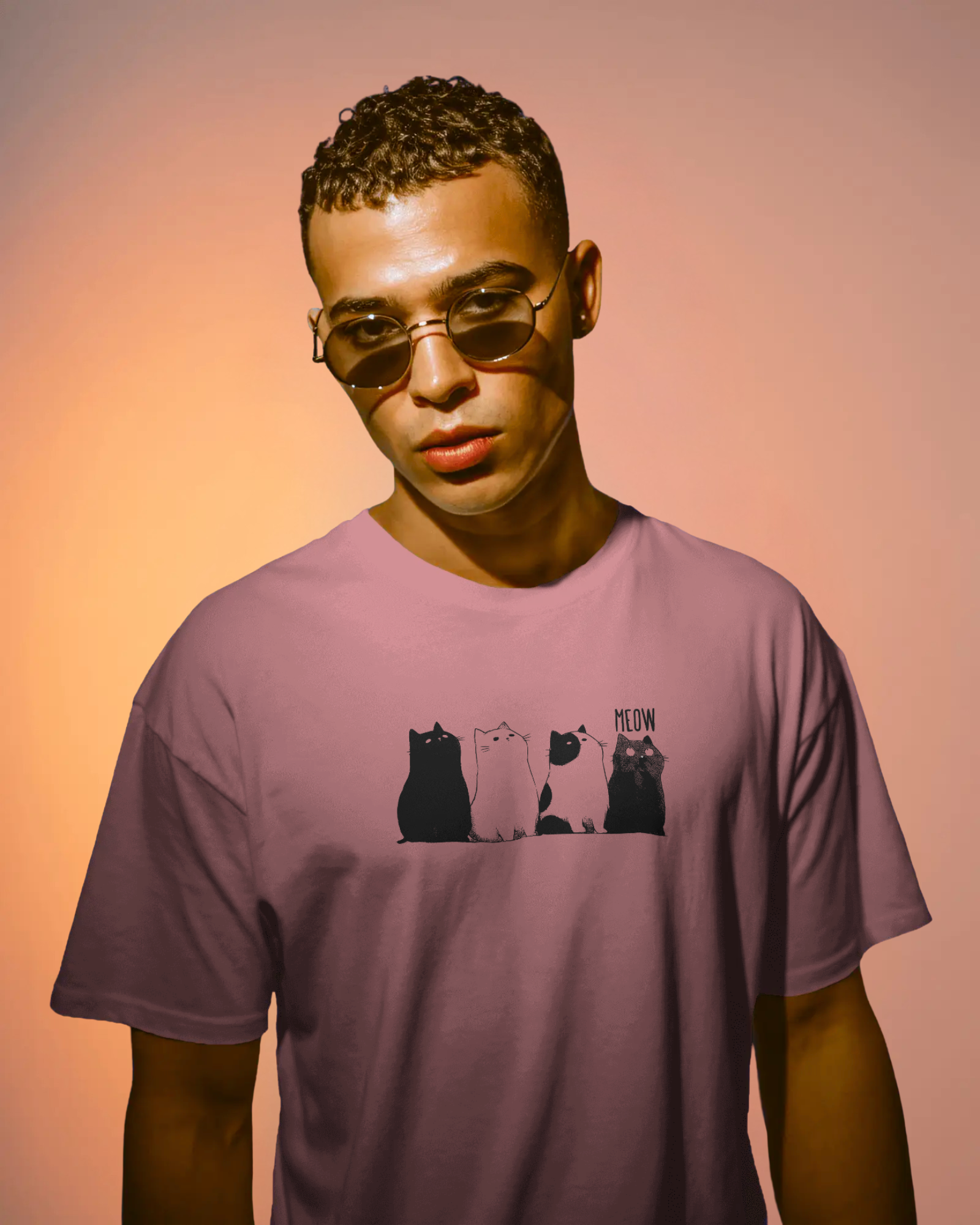 Qurrito The Purr-ple Squad graphic t-shirt in Regular Fit worn by a man with sunglasses. The Mauve/Dusty Rose tee features the Chill Cat Graphic print of four black and white cats. Chill mood.