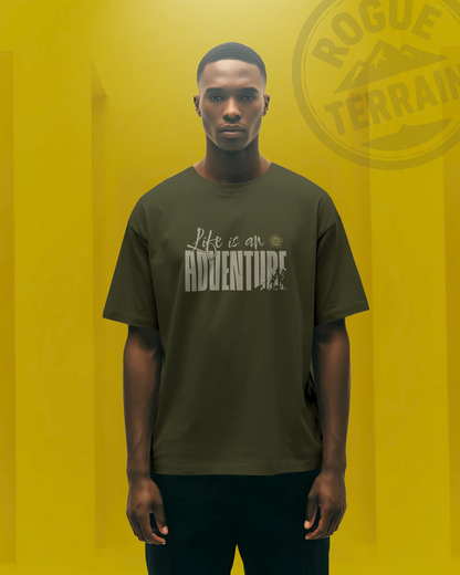 Male model wearing Qurrito’s Travel Inspired T-Shirt “Life is an Adventure” oversized tee in olive green. Crafted from premium cotton, this travel-themed streetwear tee radiates energetic, pumped, chill, relaxed, grumpy, and irritated moods — blending wanderlust spirit with bold urban fashion.