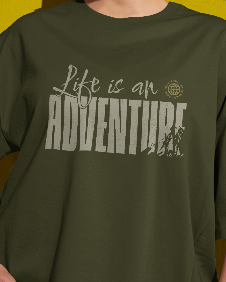 Female model styled in Qurrito’s “Life is an Adventure” Travel Inspired Oversized T-Shirt made with soft mid-heavy premium cotton. The earthy tones and relaxed silhouette express energetic, pumped, chill, relaxed, grumpy, and irritated moods — perfect for travelers and mood-driven streetwear lovers.