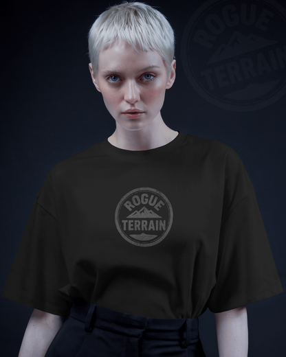 Female model wearing Qurrito’s Urban Outdoor T-Shirt in black featuring the Rogue Terrain logo printed in a subtle steel finish. This minimalistic oversized tee blends streetwear with outdoor aesthetics, reflecting chill, relaxed, serious, and focused moods for a modern urban vibe.