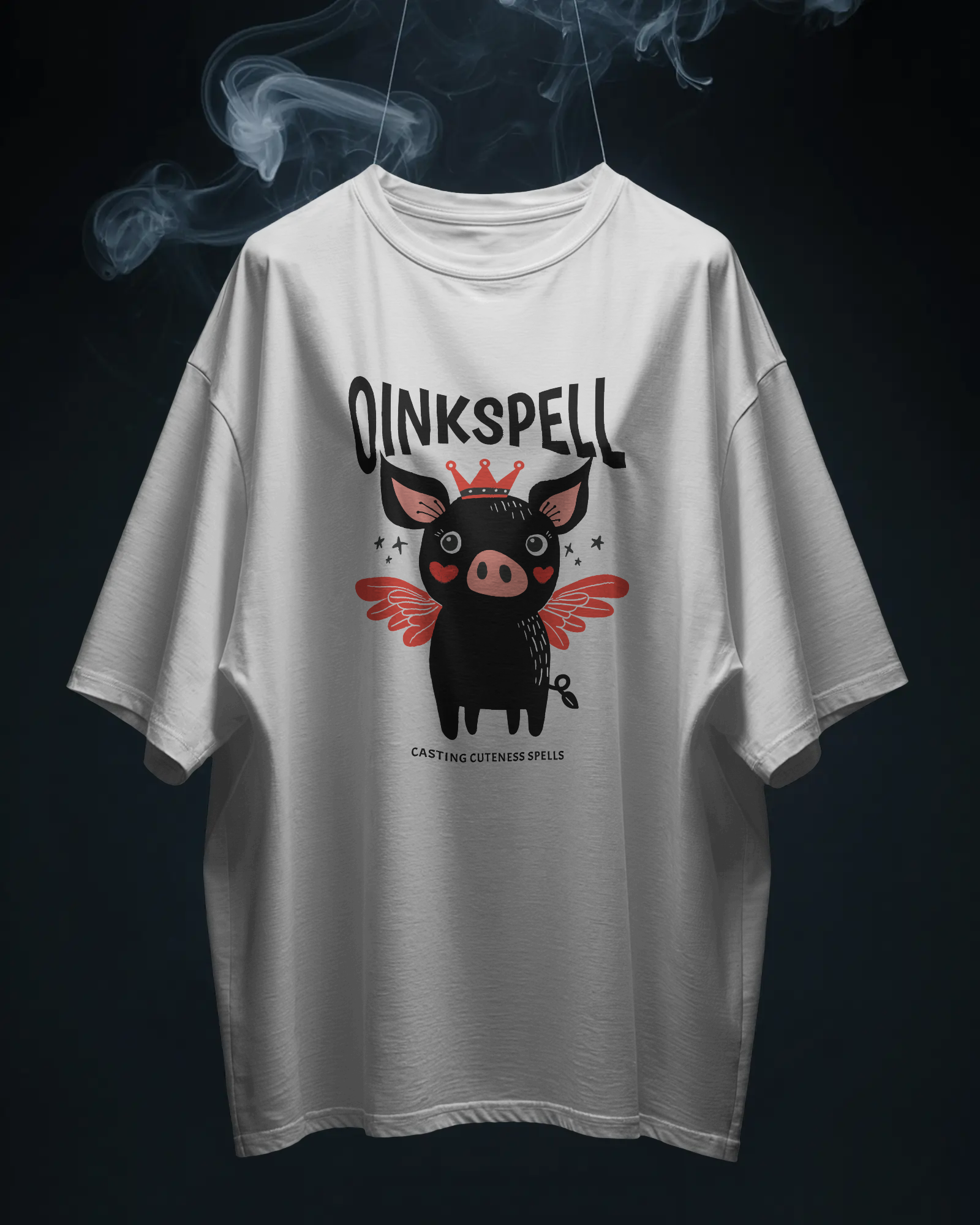 White Oinkspell Oversized T-Shirt by Qurrito, featuring a cute black pig with wings and a crown. The extra-heavy cotton gives it structure and comfort, ideal for women’s cute graphic tees and casual happy mood outfits.