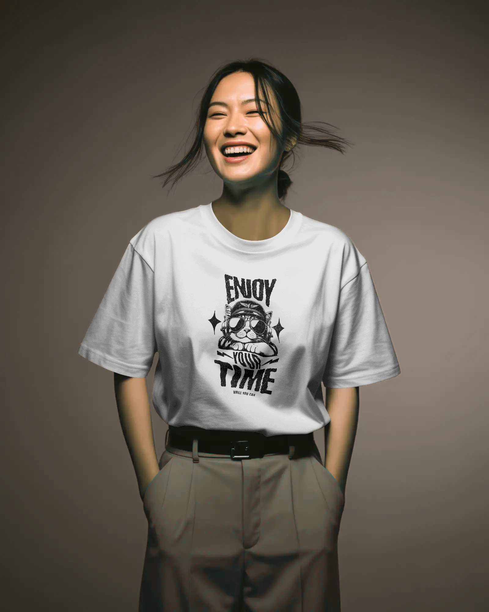 Woman wearing Qurrito’s White Oversized Positive Message T-Shirt tucked into high-waisted beige trousers, smiling effortlessly. The look exudes happy, quirky, and relaxed mood energy, ideal for modern women’s casual wear.